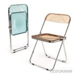 Two metal folding chairs with plastic seats and backs, one in a transparent aqua color and the other in a translucent amber color, set against a white background.