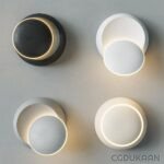 Three modern wall lights with circular design in black and white colors.